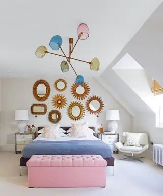 Et eksempel på ideer til soveromslysekrone som viser et soverom med en sputnik-lysekrone med flerfargede lamper over en blå seng og en rosa polstret oppbevaringsboks