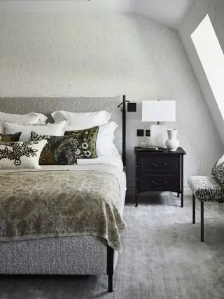 chambre grise avec tapis gris, lit texturé gris, table de chevet noire, jeté cachemire, coussins à motifs