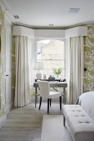 Kremfargede gardiner, grått kontorbord, hvit stol med sorte ben