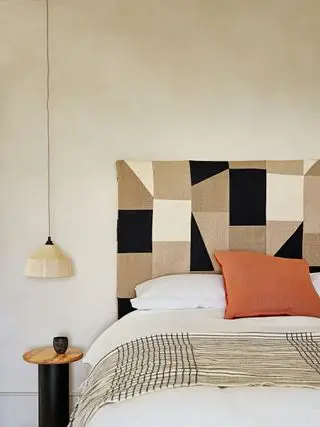 Chambre beige avec tête de lit en tissu à motifs géométriques