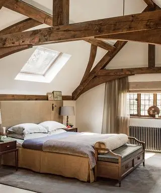 Et soverom med bjelker med jutepolstret seng og en benk i tre.