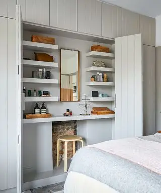 Grå innebygd skap som inneholder et toalettbord, speil og hyller.