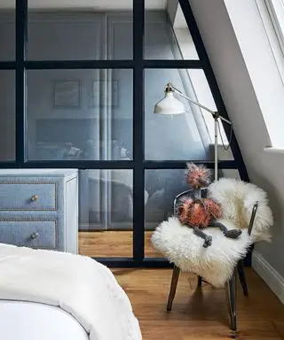 En skillevegg i glass som avskjermer grå liten soveromsoppbevaring.