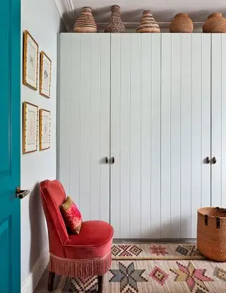 Liten soveromsbod med hvitmalt garderobeskap og mønstret teppe