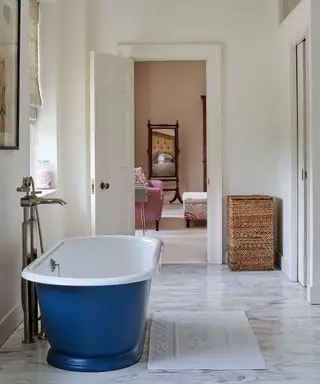 Un exemple d'idées de chambres d'hôtes montrant une salle de bain en marbre avec une baignoire sur roulettes bleue