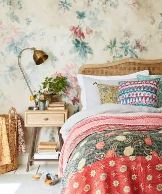 Un exemple d'idées de chambre d'amis montrant une chambre colorée avec un lit avec une tête de lit en rotin devant un papier peint floral coloré