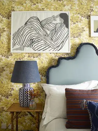 Chambre d'amis avec papier peint jaune, lampe de table et œuvres d'art
