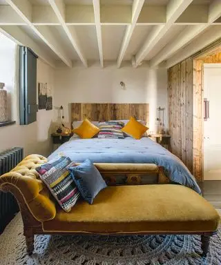 Soverom med dobbeltseng og sennepsfarget viktoriansk sjeselong på heklet teppe, tak med hvite paneler