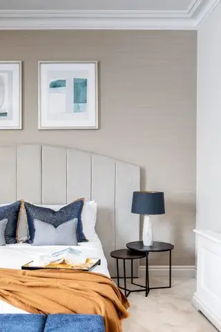 オレンジとネイビーのポップなニュートラルなベッドルーム、黒のベッドサイド テーブル ネスト