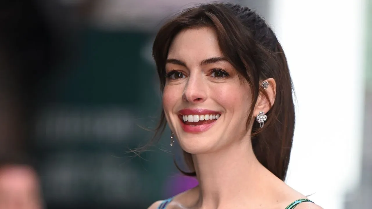 Anne Hathaway sorridente su uno sfondo grigio' loading='lazy' title=