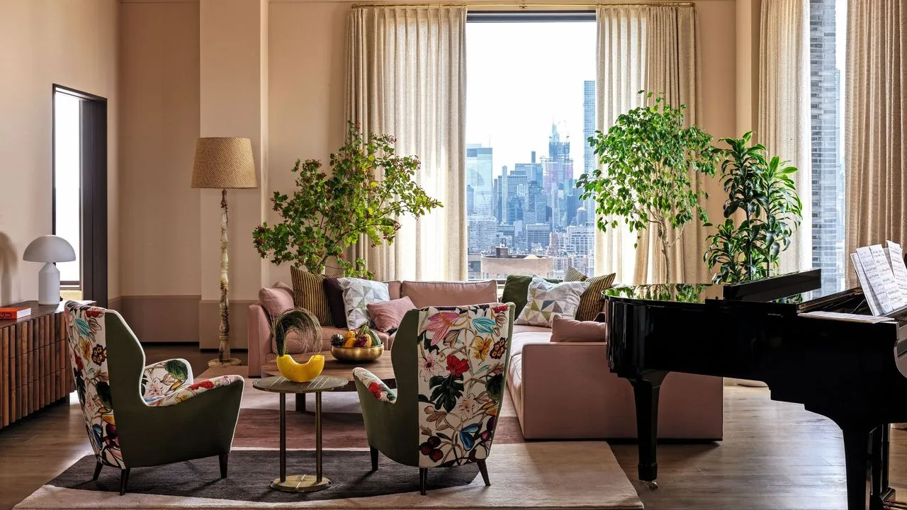 Wohnzimmer mit hellrosa Wänden und einem rosa Ecksofa mit gemusterten Sesseln und einem Flügel in der Ecke' loading='lazy' title=