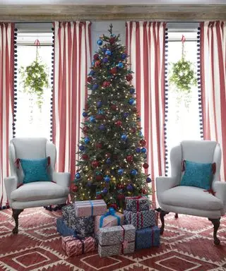 Ideias de decoração de janelas de Natal com árvore de Natal, janelas duplas com guirlandas em cada uma e decoração vermelha e azul