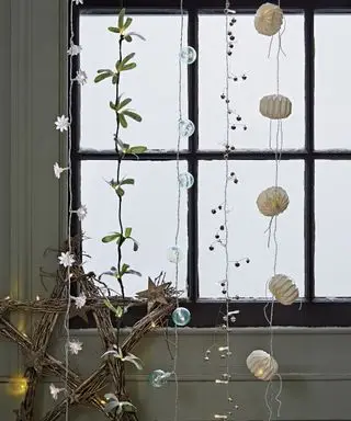 Ideias de decoração de janelas de Natal com vários estilos diferentes de luzes de fada penduradas verticalmente no topo da janela