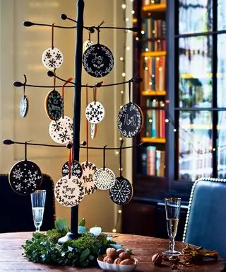 תקריב של עץ חג המולד ממתכת עם קישוטי ביסקוויטים תלויים, עלווה המקיפה את התחתית