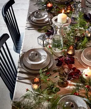 Table à manger de Noël décorée de feuillage coloré, de vaisselle, de décorations et de bougies