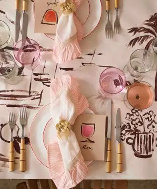 fransk-inspirert stedssetting for festmiddag, med frilly-serviett og håndmalt duk