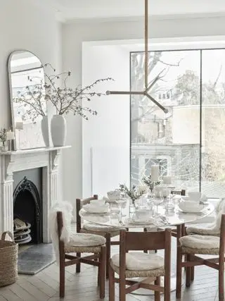 hvite høstbordsideer med saueskinnsplitter på stoler, sitteunderlag av saueskinn, hvit vase med fallgren, rustikke tre- og rottingstoler