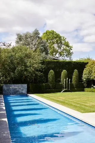 דוגמה לרעיונות לפטיו לבריכה המציגים בריכת שחייה מלבנית עם משטח מים ומדשאה