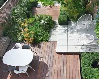 Eine Gartenterrasse in einem eleganten, modernen Design mit quadratischen Terrassendielen und überlappenden Steinterrassen.