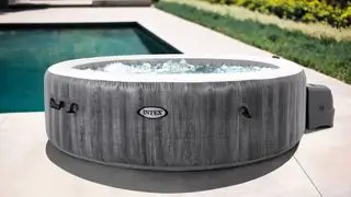 Ein Intex PureSpa Greywood Deluxe aufblasbares Whirlpool-Set – 6 Personen neben einem Pool