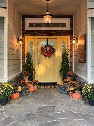 décor de porte d'entrée d'automne, porte jaune avec couronne d'automne et citrouilles