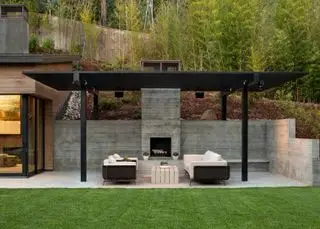 Ideen für einen schrägen Hinterhof mit einem Betonsitzbereich mit schwarzer Pergola und Außenkamin.