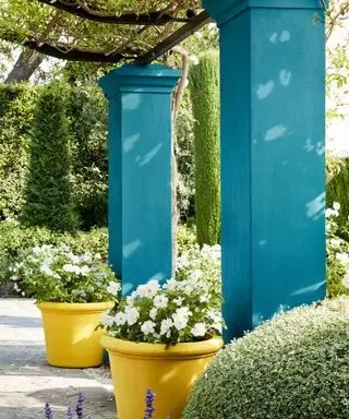 Türkis bemalte Gartensäulen mit leuchtend gelben Töpfen