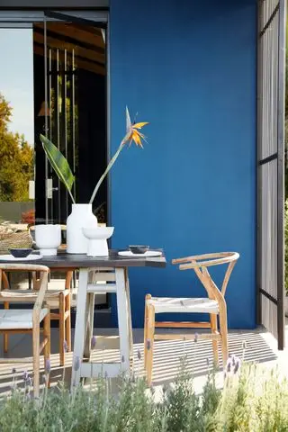 Garten-Esstisch mit blauer Wand im Hintergrund
