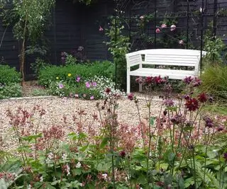 terrasse en gravier avec un banc blanc entouré de plantations