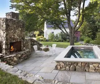 屋外暖炉のある裏庭のパティオにある大きなプランジ プール ホットタブ