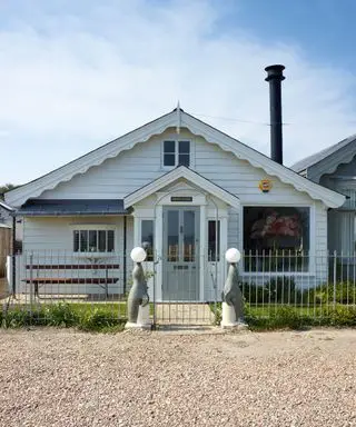 Portão de metal moderno mostrado em uma propriedade revestida de madeira à beira da praia.