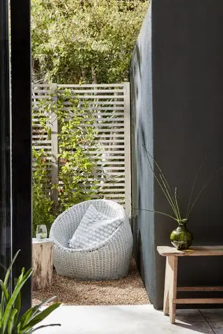Une chaise extérieure confortable repose sur du gravier au soleil