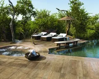 Une piscine extérieure et un bain à remous dans un jardin tropical avec chaises longues