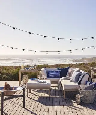 Eine Holzterrasse mit einem Sofa im Freien und Blick auf die Meereslandschaft
