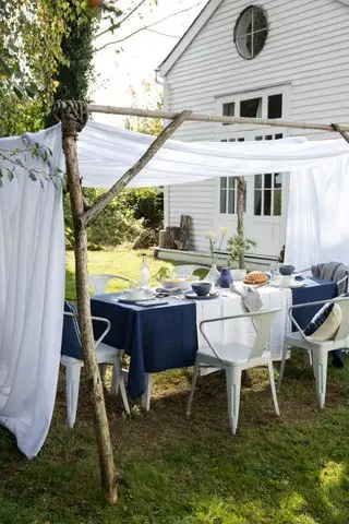 Rustikale Pergola aus Zweigen mit weißem Segel