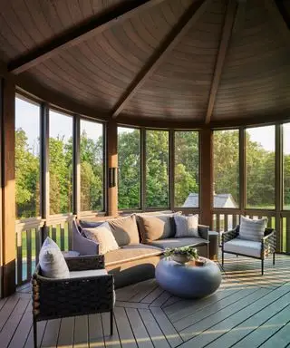 Ampia terrazza esterna, portico, soffitto rivestito in legno scuro in una struttura arrotondata, pavimento in legno scuro, divano e poltrona da esterno, tavolino rotondo