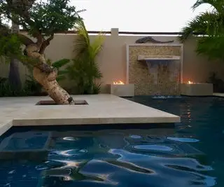 חצר אחורית מרוצפת עם בריכה, מאפייני אש ועץ מבית Gardenart Group