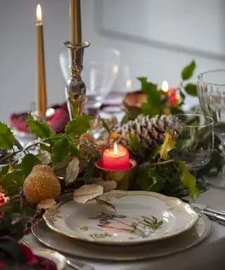 Une table de Noël décorée d'une guirlande d'épicéa de feuillage vert et de pommes de pin