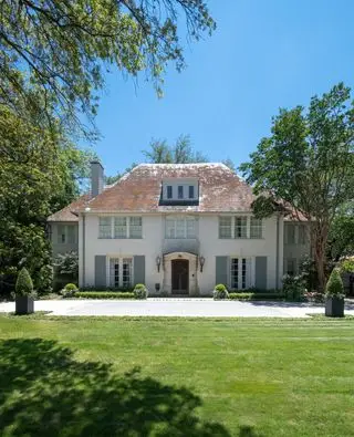 Exteriér domu vo francúzskom štýle z 20. rokov 20. storočia s bridlicovou strechou a krídlami na oboch stranách symetrickej fasády