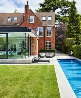 Une piscine étroite à côté de chaises longues et d'une grande maison