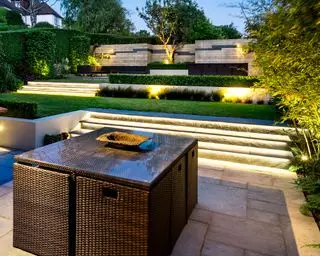 Jardin sur deux niveaux avec pelouse, pavés en béton et clôture en lattes de bois