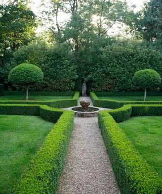 parterre de buis avec chemins de gravier autour d'une fontaine et d'une statue à l'extrémité
