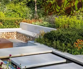 Yorkstone-Trittsteinplatten über einem Wasserspiel, das zu einem versunkenen Garten mit Steinbank und Sträuchern führt