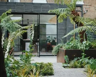 une terrasse arrière avec jardinières en acier corten et portes-fenêtres en critique