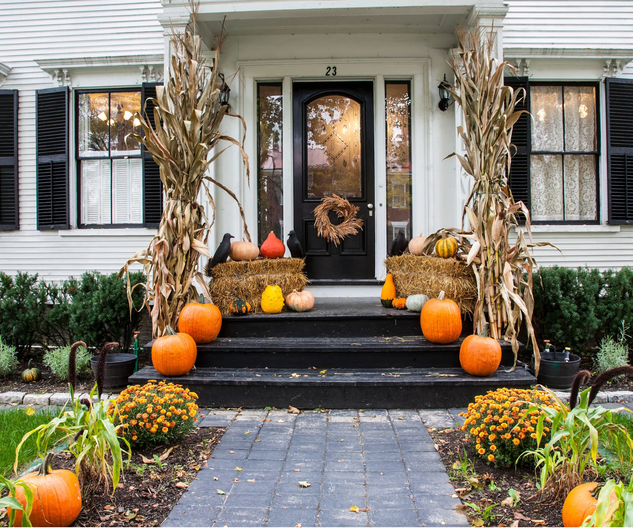 カボチャのお母さんとトウモロコシの茎のある秋のポーチ' loading='lazy' title=