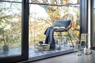 Mały balkon z płytkami podłogowymi i krzesłem z trzciny cukrowej