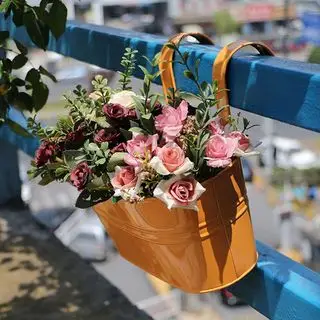 Pomarańczowa metalowa wisząca donica na balustradę balkonową