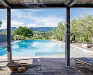 La vue d'une piscine entourée d'arbres sous une pergola avec terrasse