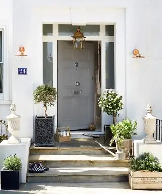 porta d'ingresso grigia con due applique e una lampada a sospensione sospesa dall'alto