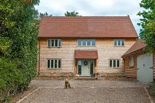 dřevěný opláštěný dům se zelenými dveřmi a okny s přístavbou garáže